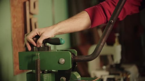 A Man Cuts a Piece of Leather Off the Blank Using a Press