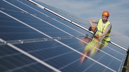 Male Engineer in a Uniform Is Checking the Solar Battery Outside