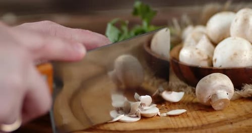 Man's Hand Crushed Fresh Mushrooms with a Large Knife