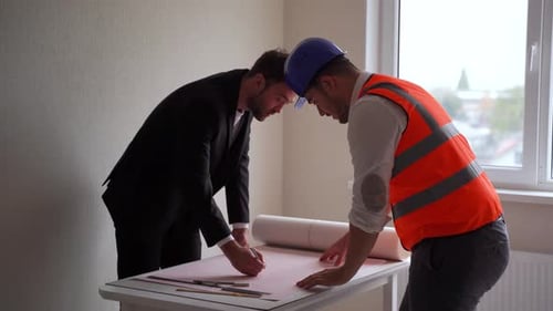 Men Inspecting Blueprints in a Bright Office