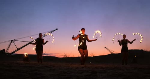 Fire Show Three Women in Their Hands Twist Burning Spears and Fans in the Sand with a Man with Two