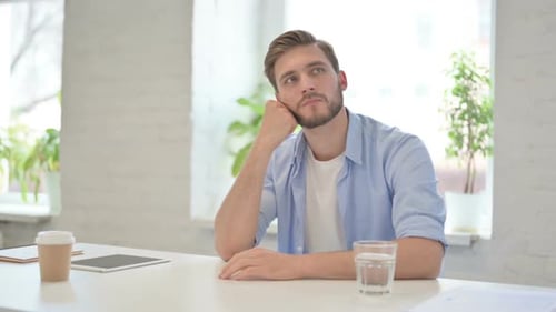 Young Creative Man Sitting in Modern Office Thinking