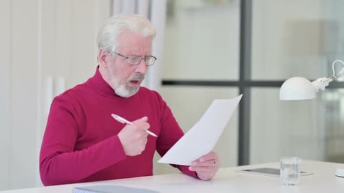 Senior Man Arguing with Documents at Desk