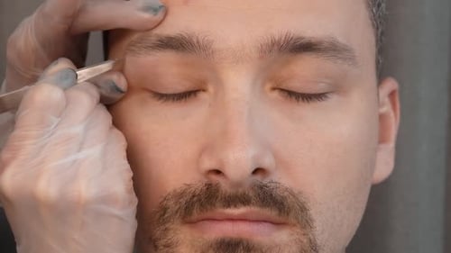 Man Getting Eyebrows Groomed with Tweezers Close Up