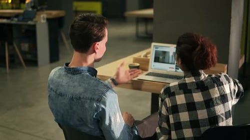 Two Young Adults Collaborating at a Modern Workplace