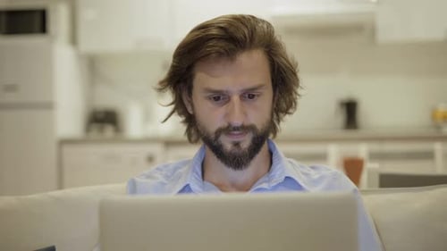 Close-up of Concentrated Man with Beard Typing on Tablet