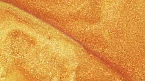 Areia dourada colorida se move organicamente em líquido colorido em macro