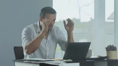 Geschäftsmann bekommt schlechte Nachrichten. Depressiver männlicher Freelancer arbeitet am Laptop