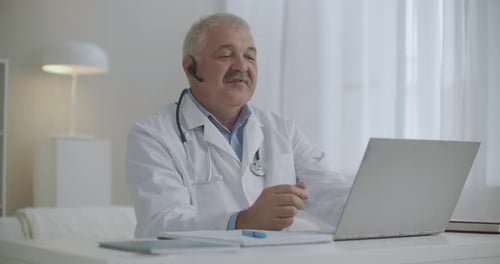 Freundlicher fröhlicher Arzt berät online, arbeitet per Internet mit Patienten, Chatten per Videoanruf