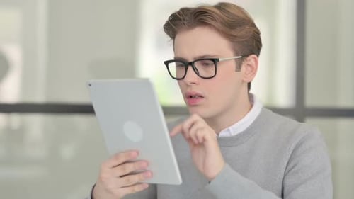 Young Man Reacting to Loss on Tablet in Modern Office