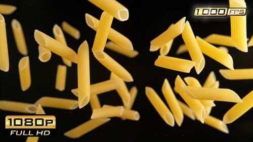 Penne pasta falling in slow motion on black backdrop