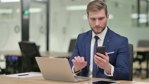 Man in Suit Using Phone at Office Desk
