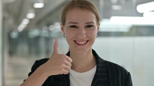 Smiling Woman Giving Thumbs Up in Office