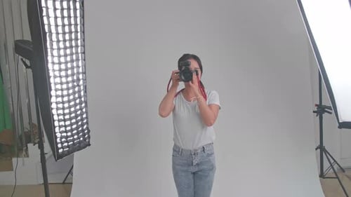 Young Asian Female Photographer Standing And Taking Photos In Studio