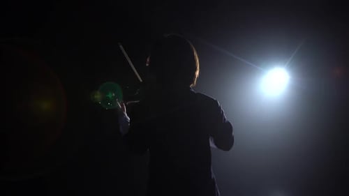 Professional Playing the Violin in a Dark Studio with a Lantern From It Glare