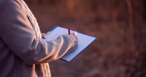 Close Up of Female Writing Alert Inscription at Clipboard