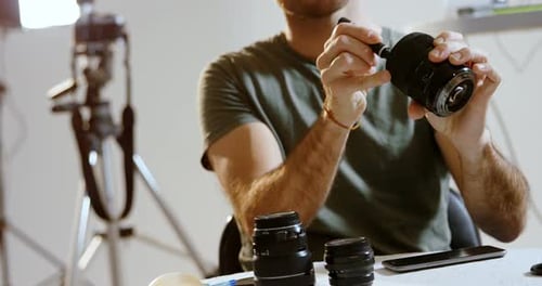 Male photographer cleaning camera lens