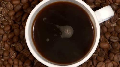 Xícara branca com barracas de café em feijão marrom, embalagem, close up