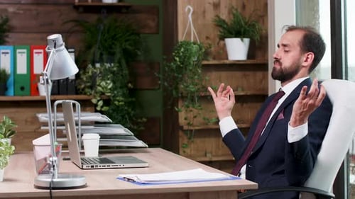 Bearded Man Meditates in Office During Rainy Day