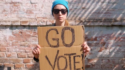 Woman shows cardboard Go Vote sign Voting balloting polling Political choice elections voice 4K