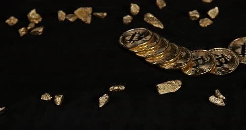Bitcoins y pepitas de oro, pepita, caída sobre fondo negro, cámara lenta 4K