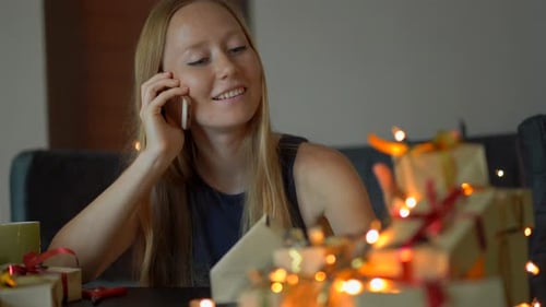 Woman Talks on Phone While Wrapping Gifts