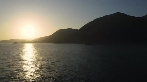 Flying above sea at Sunrise. Aerial view of Sunrise over Ocean. Mountain near coast.
