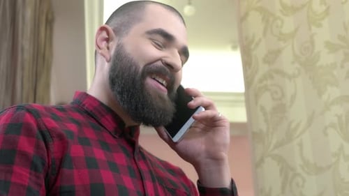 Fröhlicher bärtiger Mann mit Telefon