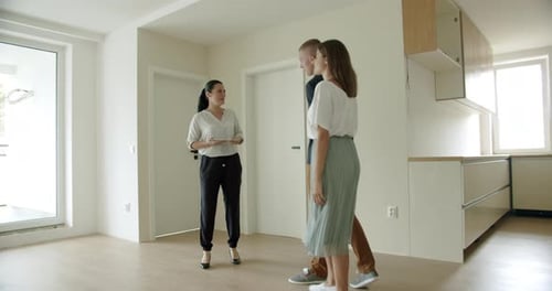 Estate Agent and Young Couple Looking at New Apartment With Digital Tablet
