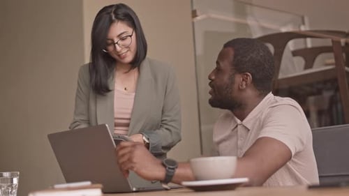 Diverse Colleagues Working on Project Together in Cafe