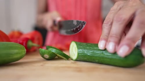 Slicing Fresh Cucumber on Wooden Cutting Board
