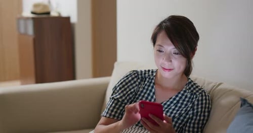 Woman using smartphone on couch at night