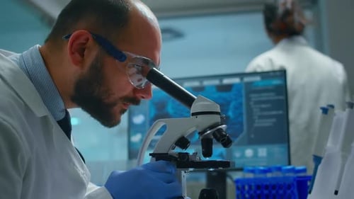 Lab Technician Examining Samples and Liquid Using Microscope