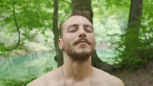 Man Meditates in Green Forest, Opens Eyes