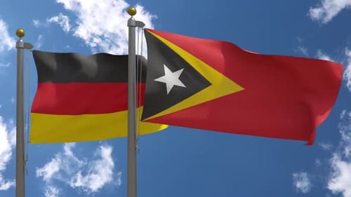 Realistic Waving Flags of Germany and East Timor against Blue Sky