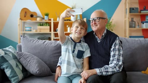 Grandfather and Grandson Take Selfie Together Indoors