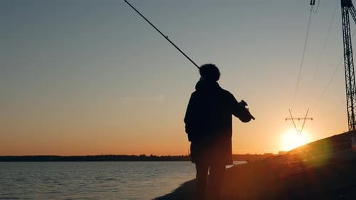 Ein Schuss vom Rücken eines Fischers vor dem Hintergrund des Sonnenuntergangs. Die Kamera bewegt sich nach dem