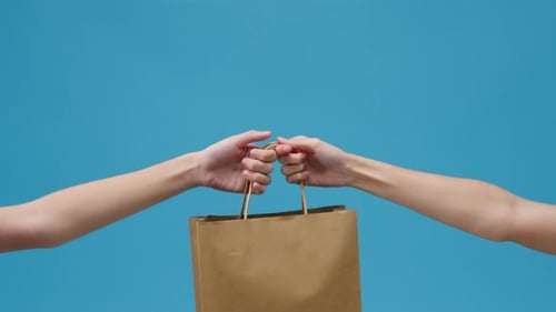 Arms Pass Brown Paper Bag Against Blue Background