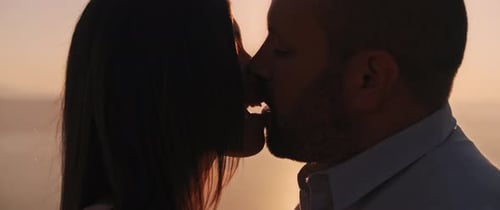 Close up of a young couple kissing at sunset, with beautiful sun flare behind them.