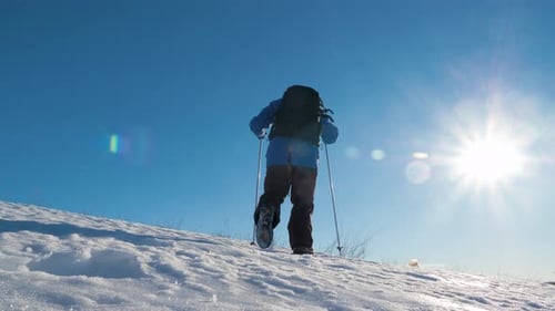 Hiker Ascending Snowy Hill on Sunny Winter Day