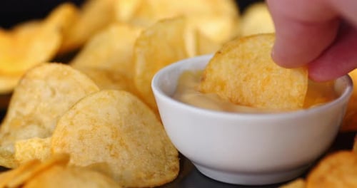 Dipping Potato Chip in Bowl of Sauce