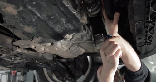 Mechanic Adjusting Car Underside in Auto Repair Shop