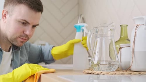 Man Cleaning Kitchen Counter with Yellow Gloves