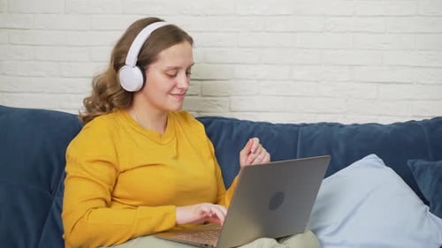 Woman Enjoys Music While Working on Laptop