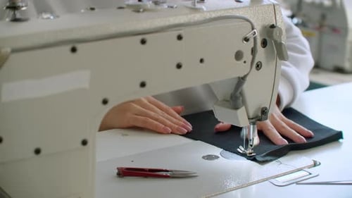 Woman Sewing Black Fabric on Machine Close Up