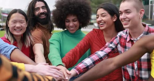 Young multiethnic people having fun stacking hands outdoor