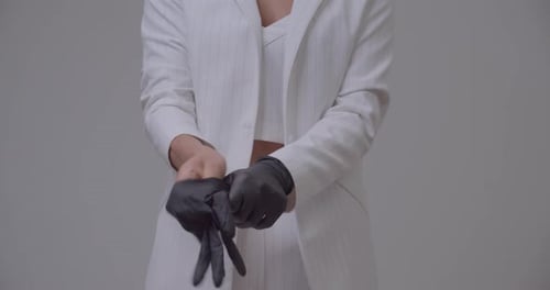Woman Putting On Black Gloves With White Outfit