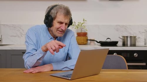 Mature Man Using Laptop with Headphones at Home