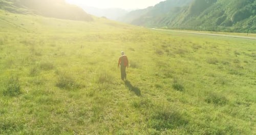Flight Over Backpack Hiking Tourist Walking Across Green Mountain Field