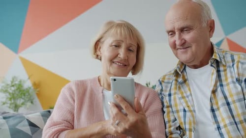 Smiling Senior Couple Using a Smartphone Together Indoors